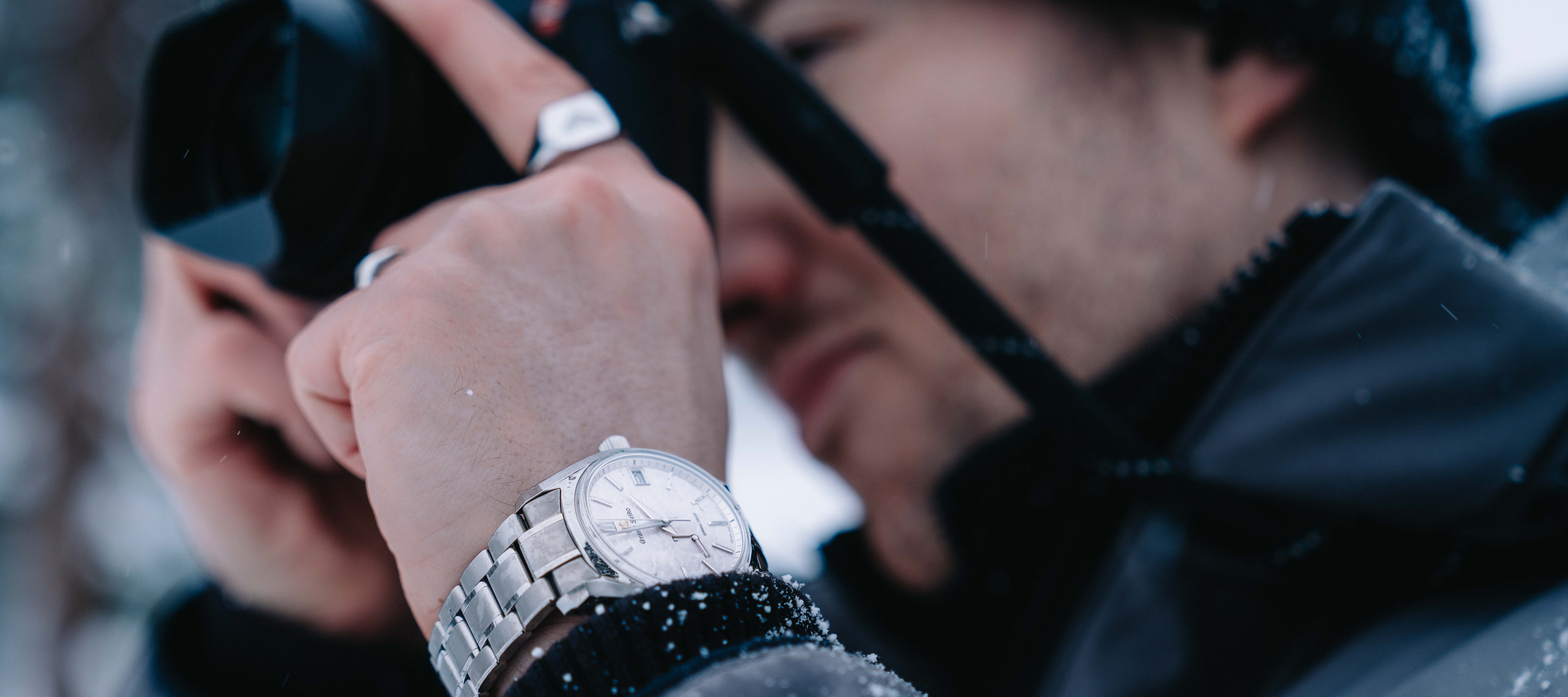 A man taking a photograph with a silver watch on his wrist
